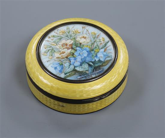 An early 20th century silver and enamel circular box and cover with central painted floral panel, 65mm.